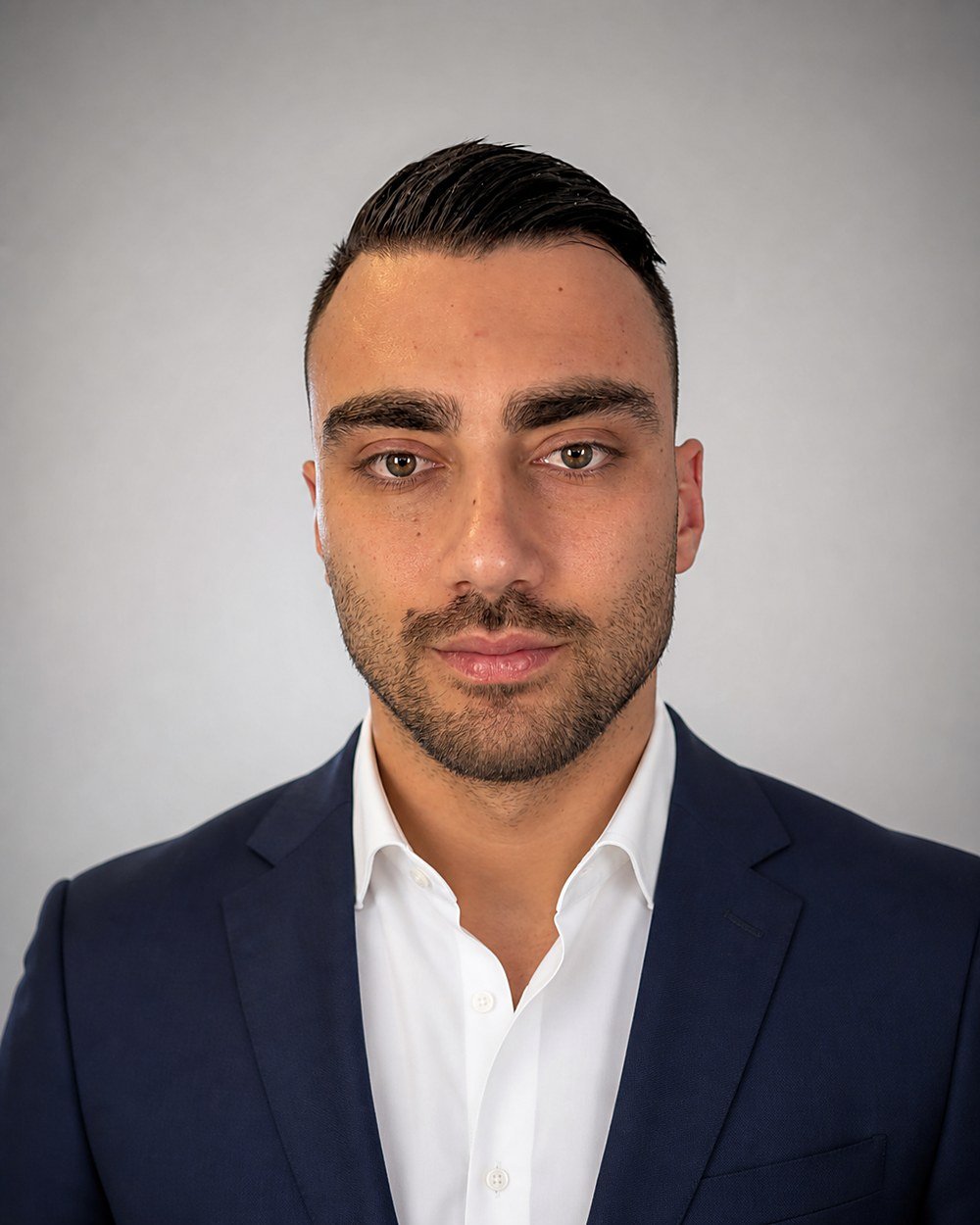 Zakelijk portret van Emre Karaahmet in donkerblauw colbert met wit overhemd.